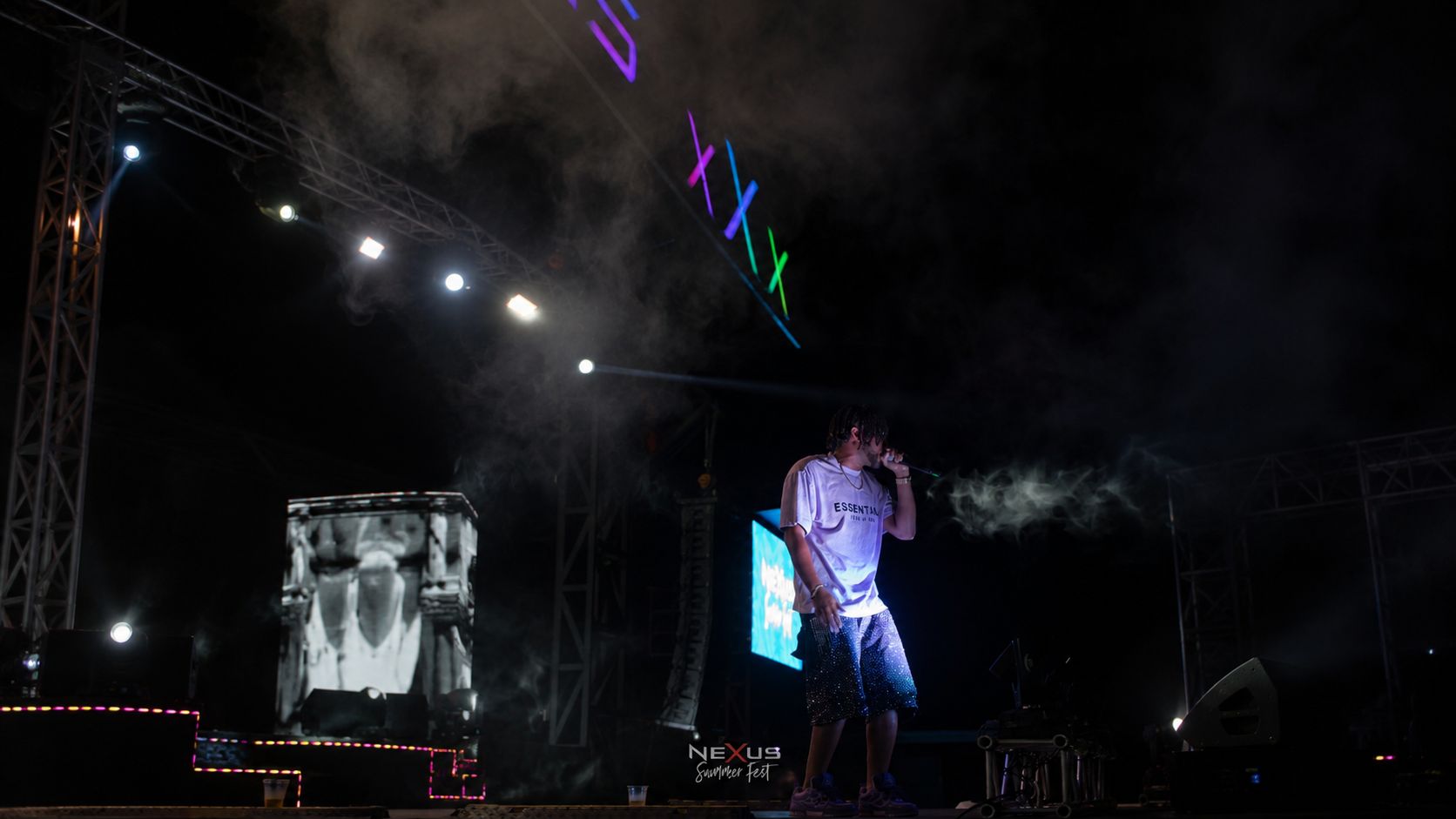 Artista en el escenario de un concierto nocturno entre luces de colores y humo